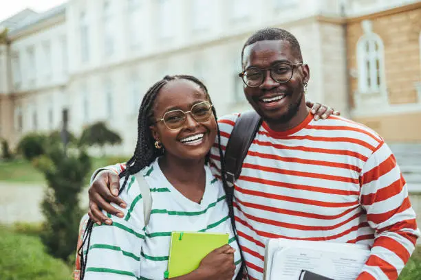 Two African students smiling outside a building